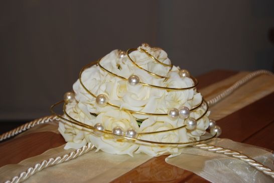 Nahaufnahme einer Sargdekoration aus weißen Rosen, Perlen und Goldband