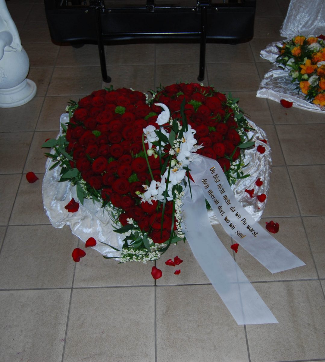 Großes Herz aus roten Rosen mit weißer Umrandung und Schleife